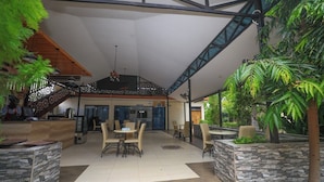A spacious indoor area with a high ceiling, a reception desk, multiple seating arrangements, and a staircase leading to an upper level. - The Heritage Resort (Wajir)