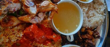 Un plato de metal con arroz, pollo, carne y dos tazones de sopa.