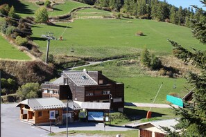 Un bâtiment moderne doté d’un toit en pente, d’une petite structure attenante et offrant une vue dégagée sur une colline verdoyante.