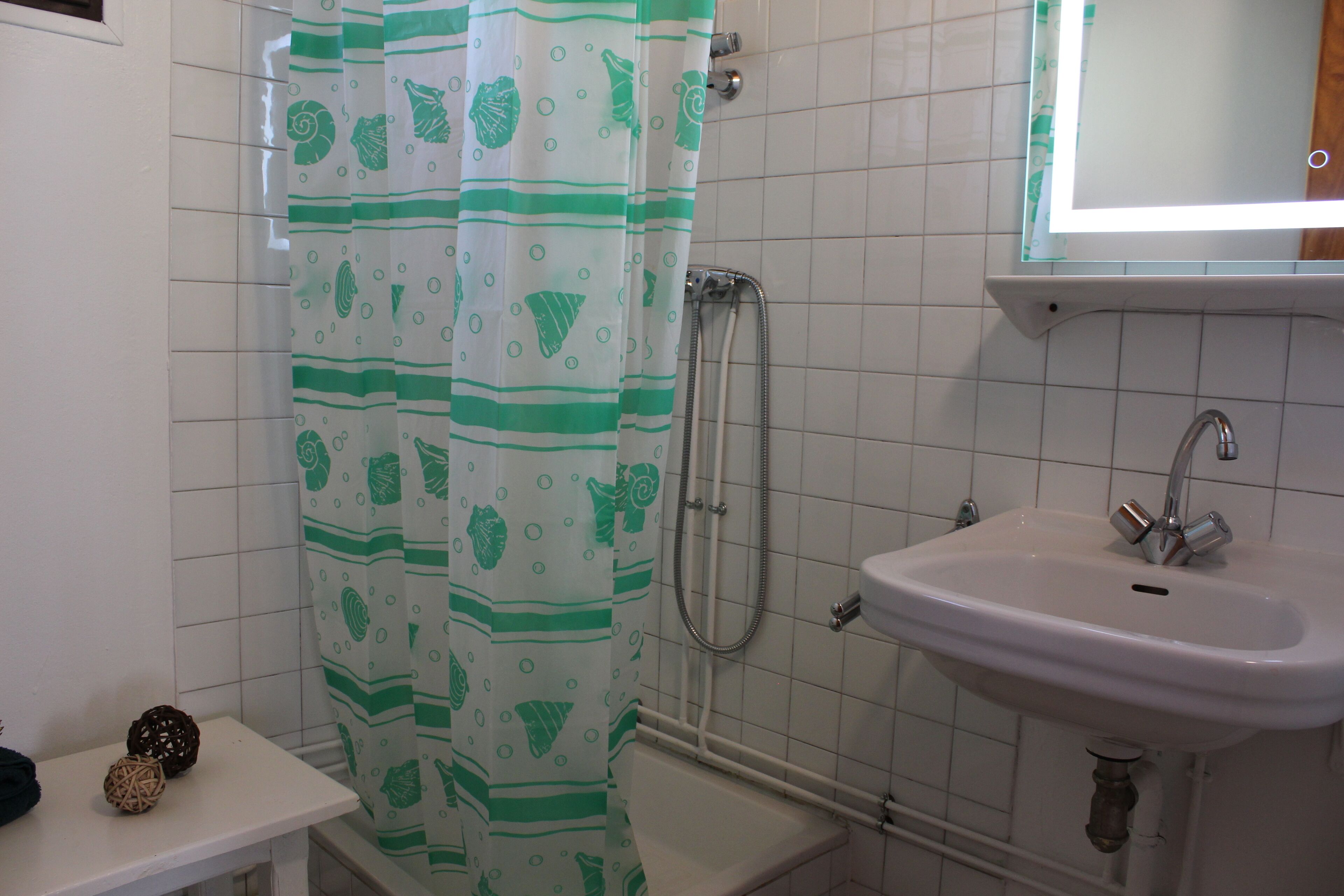 Une salle de bain avec un rideau de douche, un lavabo et un miroir.