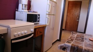 Una cucina compatta con forno a microonde, forno e frigorifero.
