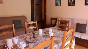 Un'area pranzo con un tavolo apparecchiato per quattro persone, circondato da sedie in legno. Sul tavolo ci sono quattro tazze bianche e una candela.