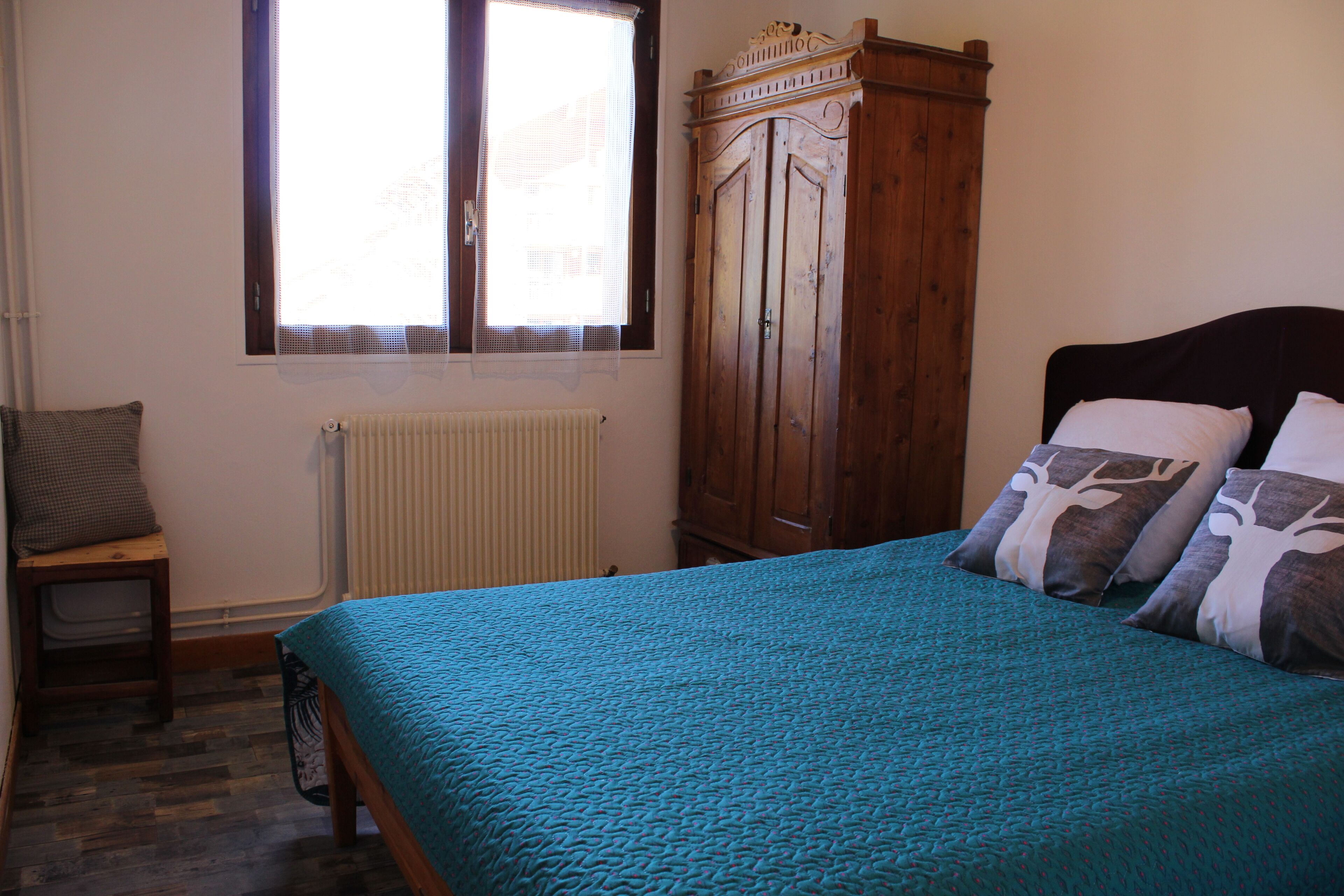 A bedroom with a bed, a wardrobe, a window, and a radiator.
