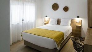 Un dormitorio ordenado con cama, mesitas de noche y una silla.
