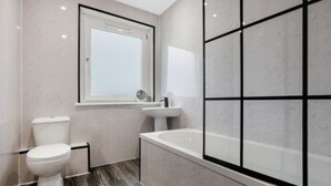 A modern bathroom with a toilet, sink, and bathtub. - Free Parking | Central | Sleeps 6 | 3 Bedrooms (North Lanarkshire)