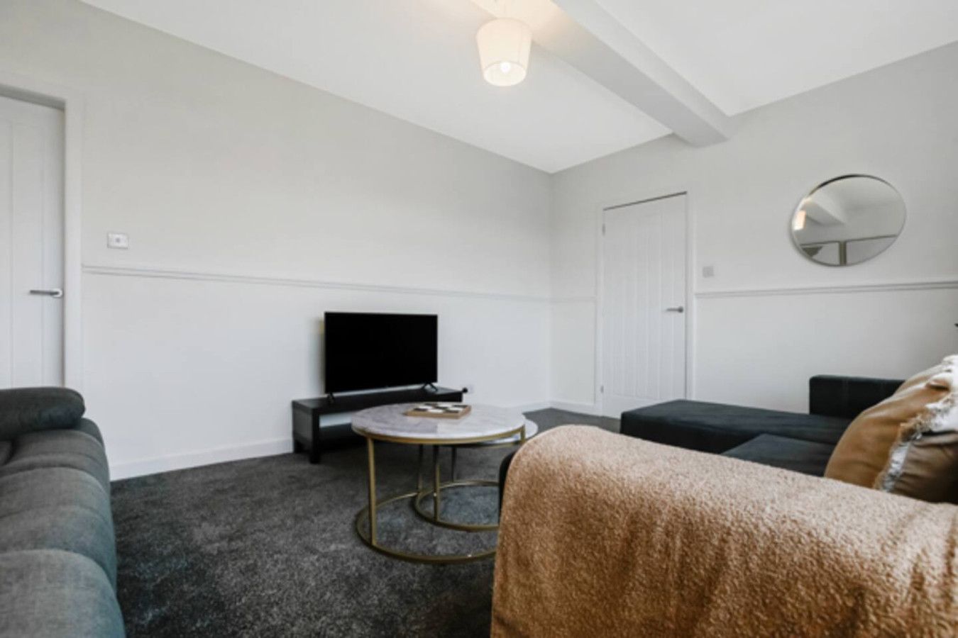 A living room with a flat-screen TV, a round coffee table, and a sofa.