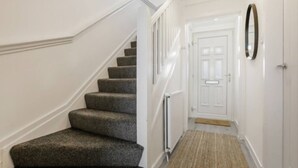 A staircase with carpeted steps leading to a white door. - Free Parking | Central | Sleeps 6 | 3 Bedrooms (North Lanarkshire)