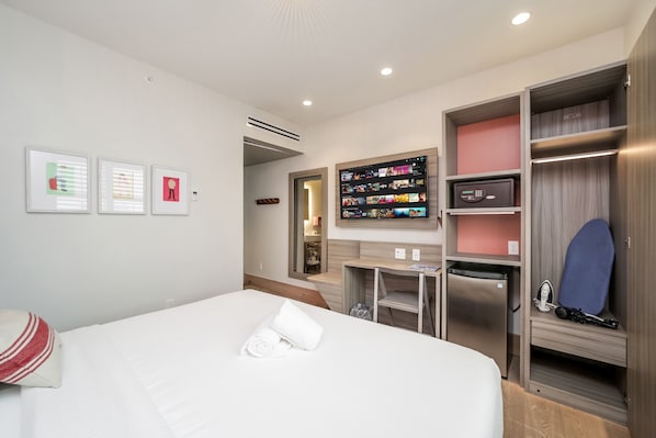 A hotel room with a bed, a TV mounted on the wall, a mini-fridge, a microwave, and a wardrobe. - The Julia Hotel By At Mine Hospitality (Miami Beach)