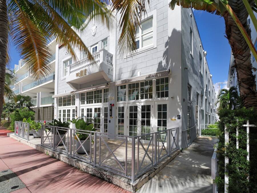 A modern building with multiple balconies, large windows, and a gated entrance.