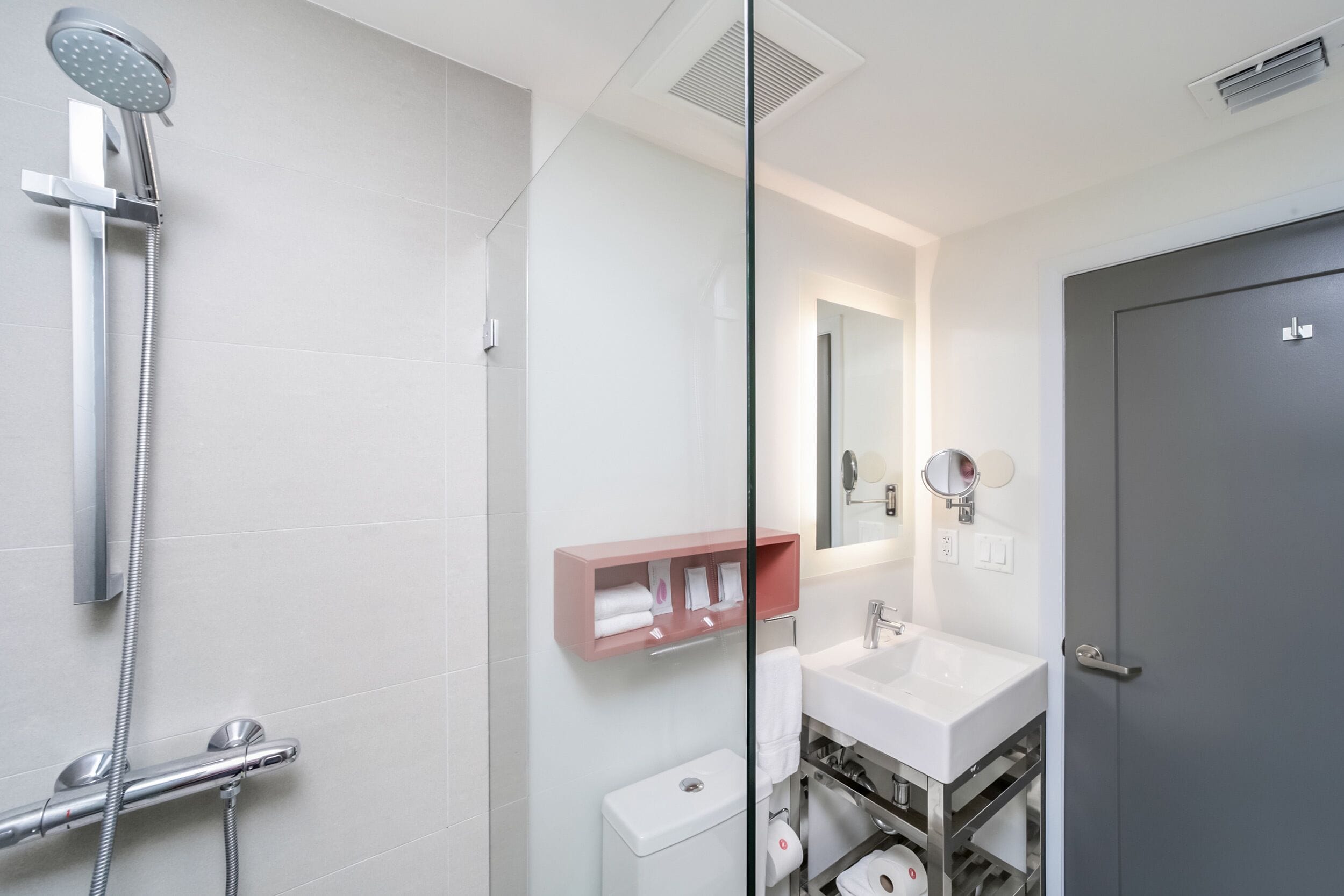 A modern bathroom with a shower, toilet, sink, and a mirror.