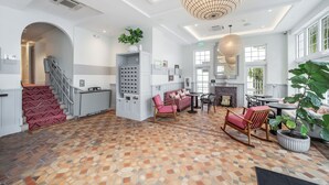 Eine gro ßzügige Lobby mit einem gemusterten Boden, einer Treppe, einer Sitzecke und einer großen Kronleuchter.
