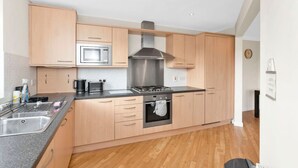 A modern kitchen with wooden cabinets, a stainless steel range hood, a microwave, and a gas stove.