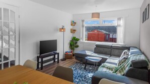 A modern living room with a sofa, TV, and dining table.