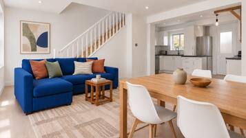 Un salon moderne avec un canapé bleu, une table basse en bois et une table à manger avec des chaises blanches.