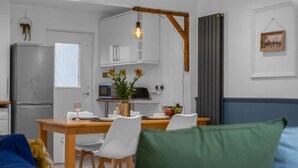 A modern kitchen with white cabinets, a wooden dining table, and a hanging light fixture. - Free Parking | Central | Sleeps 5 | 2 Bedrooms (West Lothian)