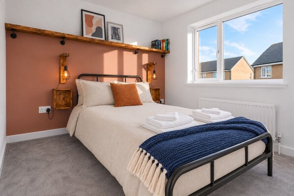 Un dormitorio con cama, ventana, radiador y una estanter ía con libros.