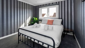 A bedroom with a bed, a window, and a plant.