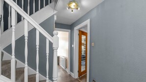 A hallway with a wooden staircase, a door with a glass panel, and a ceiling light fixture.