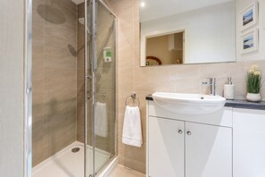 Une salle de bain moderne avec une douche à parois de verre, un lavabo blanc et un miroir au-dessus du lavabo.