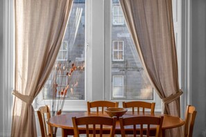 A dining table with chairs, a bowl, and a window with curtains. - Free Parking | City Centre | Sleeps 9 | 3 Bedrooms (Edinburgh)