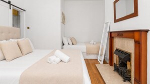 A hotel room with a bed, a sofa, a fireplace, and a mirror. - Stunning 1-Bedroom Flat in Edinburgh | Sleeps 3 (Edinburgh)