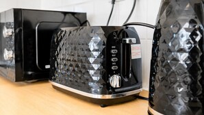 A kitchen with a modern toaster and a kettle on a wooden countertop. - Stunning 1-Bedroom Flat in Edinburgh | Sleeps 3 (Edinburgh)