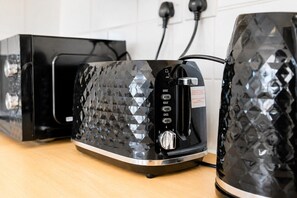 A kitchen with a modern toaster and a kettle on a wooden countertop. - Stunning 1-Bedroom Flat in Edinburgh | Sleeps 3 (Edinburgh)