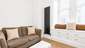 A living room with a brown sofa, white coffee table, and a white dresser with drawers. - Stunning 1-Bedroom Flat in Edinburgh | Sleeps 3 (Edinburgh)