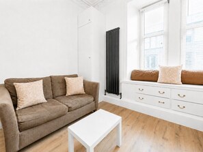A living room with a brown sofa, white coffee table, and a white dresser with drawers. - Stunning 1-Bedroom Flat in Edinburgh | Sleeps 3 (Edinburgh)