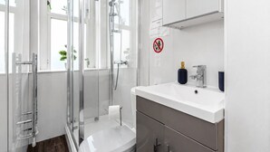 Un bagno moderno con box doccia in vetro, un water bianco e un lavandino con uno specchio sopra.