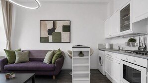 Una cucina moderna con mobili bianchi, forno integrato e un piano di lavoro con un bollitore.