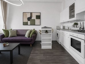 Eine moderne Küche mit weißen Schränken, einem eingebauten Backofen und einer Arbeitsplatte mit einem Wasserkocher.