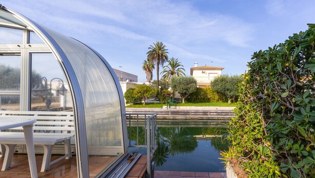 Eine moderne, geschwungene Glasarchitektur mit einer Bank und einem kleinen Pool.