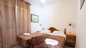 Ein Doppelbett mit brauner Bettdecke, ein Nachttisch aus Holz mit einer Lampe und ein Bild an der Wand.