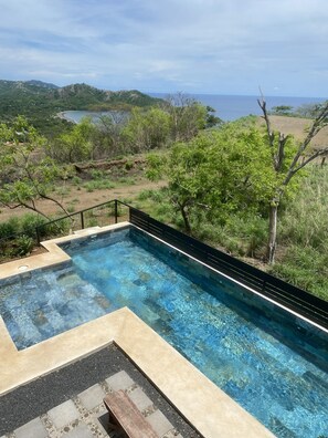 Une piscine aux eaux cristallines, avec vue sur la mer et les collines en arrière-plan.