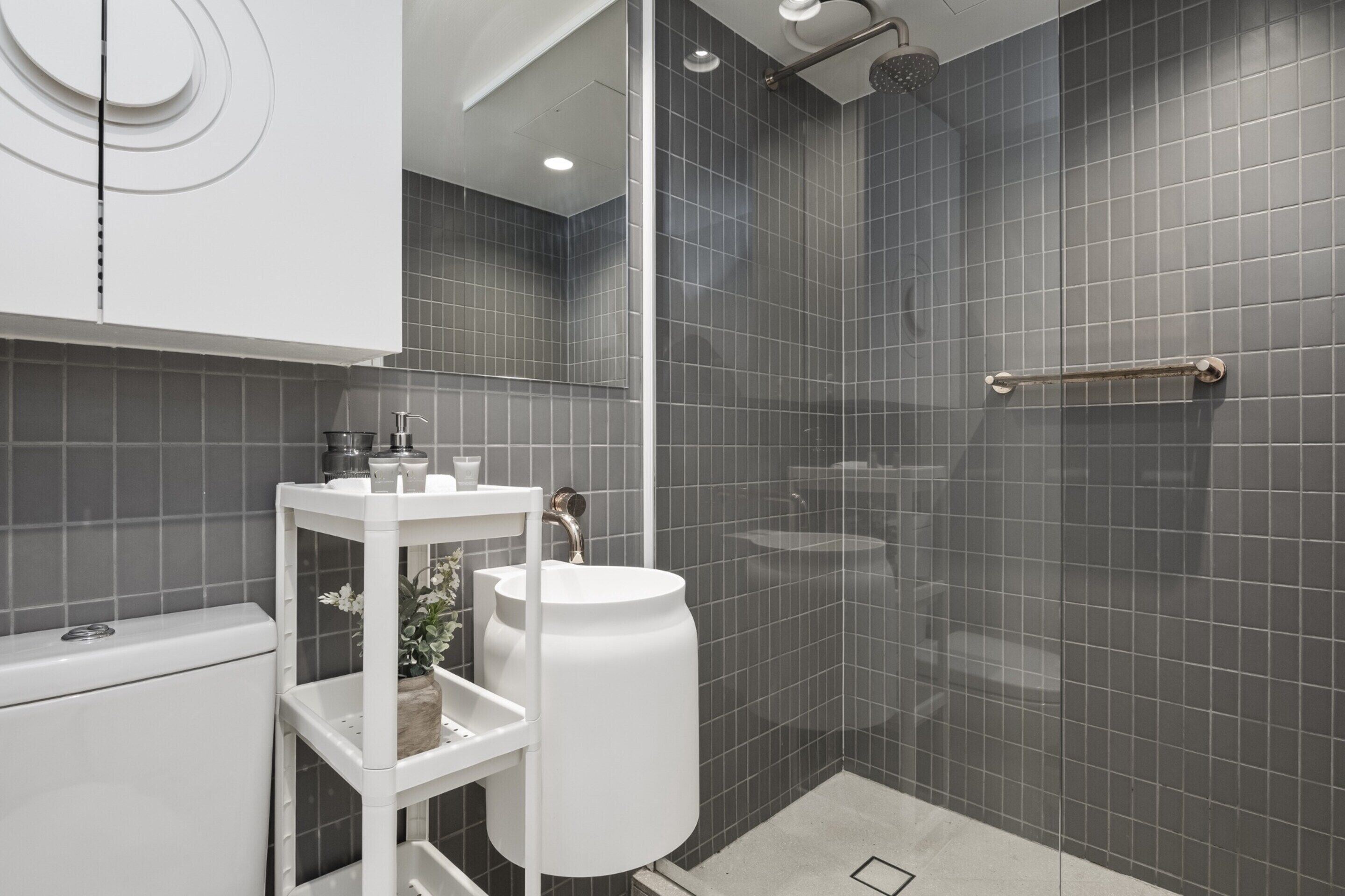 Een moderne badkamer met een witte wastafel, een douchecabine van glas en een handdoekrek.