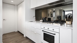Eine moderne Küche mit weißen Schränken, einem Gasherd und einem eingebauten Backofen.