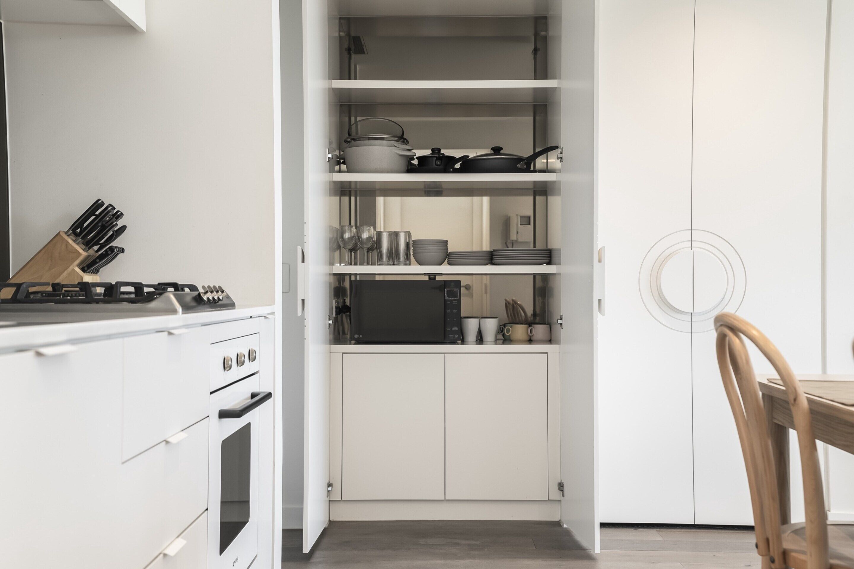 Una cucina con mobili bianchi, un piano cottura e una zona pranzo con un tavolo e sedie di legno.