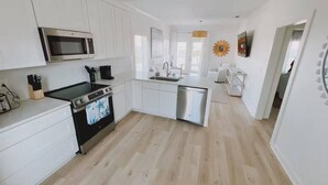 Una cucina moderna con mobili bianchi, forno in acciaio inox e lavastoviglie.