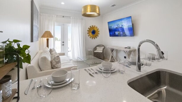 Een moderne keuken met een centraal eiland, een RVS-spoelbak en een zithoek met een bank en tafel.