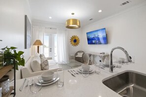 A modern kitchen with a central island, stainless steel sink, and a dining area with a sofa and table. - Weekend Escape on the Coast - Relax & Unwind (Pass Christian)