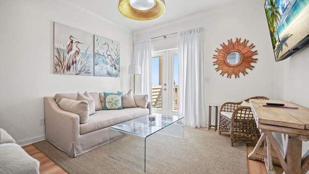 Un salon moderne avec une table basse en verre, un canapé beige et un coin repas avec des chaises en osier.
