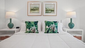 Una camera d'albergo con un letto grande, due comodini, due lampade e due quadri appesi alla parete.