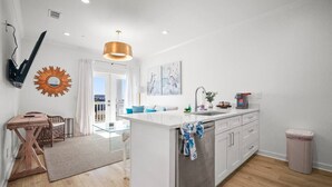 Una cucina moderna con isola centrale, mobili bianchi e vista all'esterno.