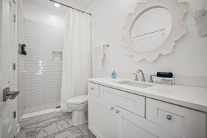 Ein modernes Badezimmer mit einer weißen Duschkabine, Toilette, Waschtisch und Spiegel.
