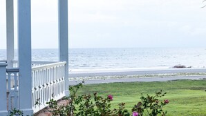 A covered porch with a view of the ocean and a grassy area with flowers. - Pass Christian 3BR Townhome - Pool - Sleeps 6 (Pass Christian)