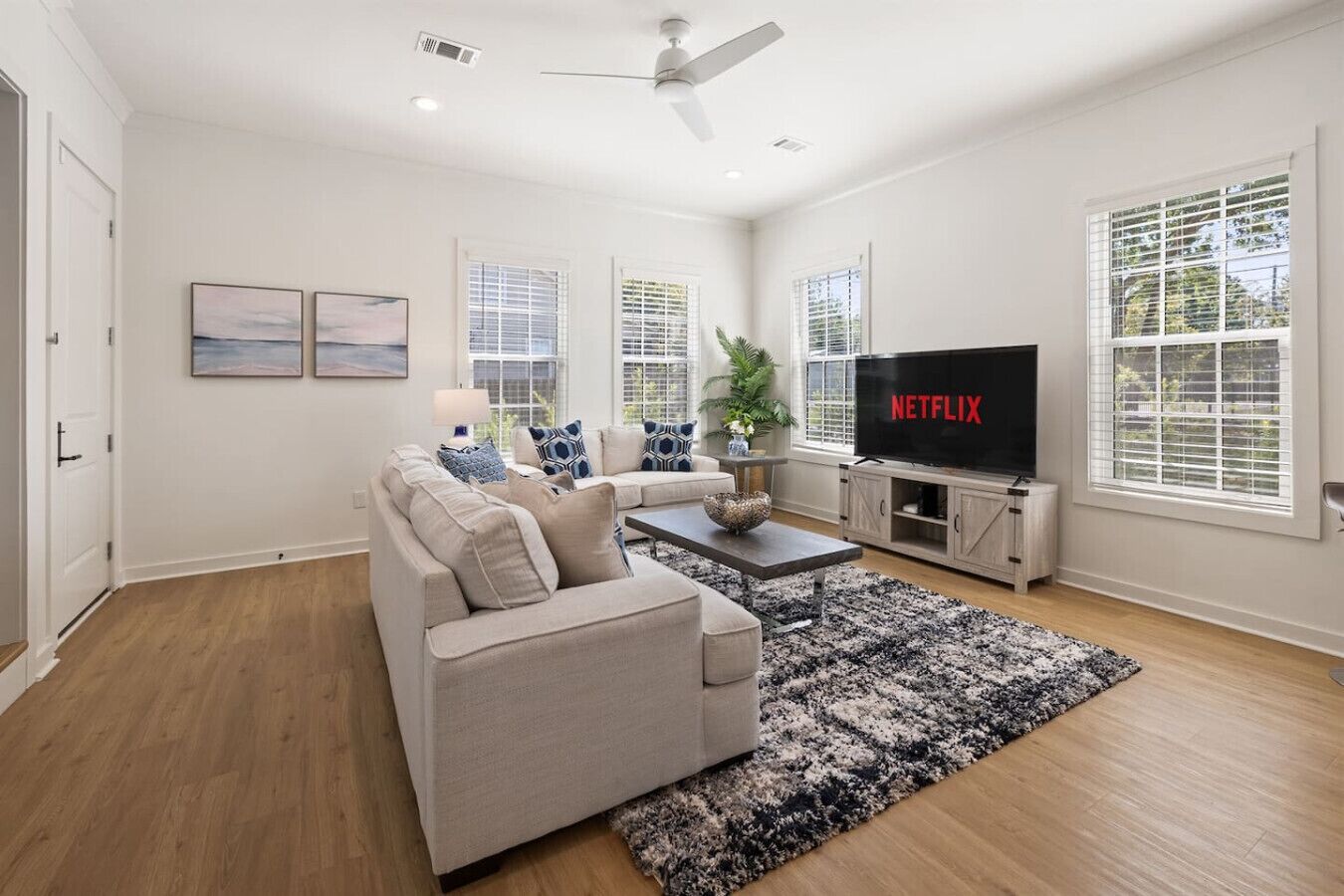 Ein modernes Wohnzimmer mit einem beigen Sofa, einem Couchtisch und einem Fernseher, der 'NETFLIX' zeigt.