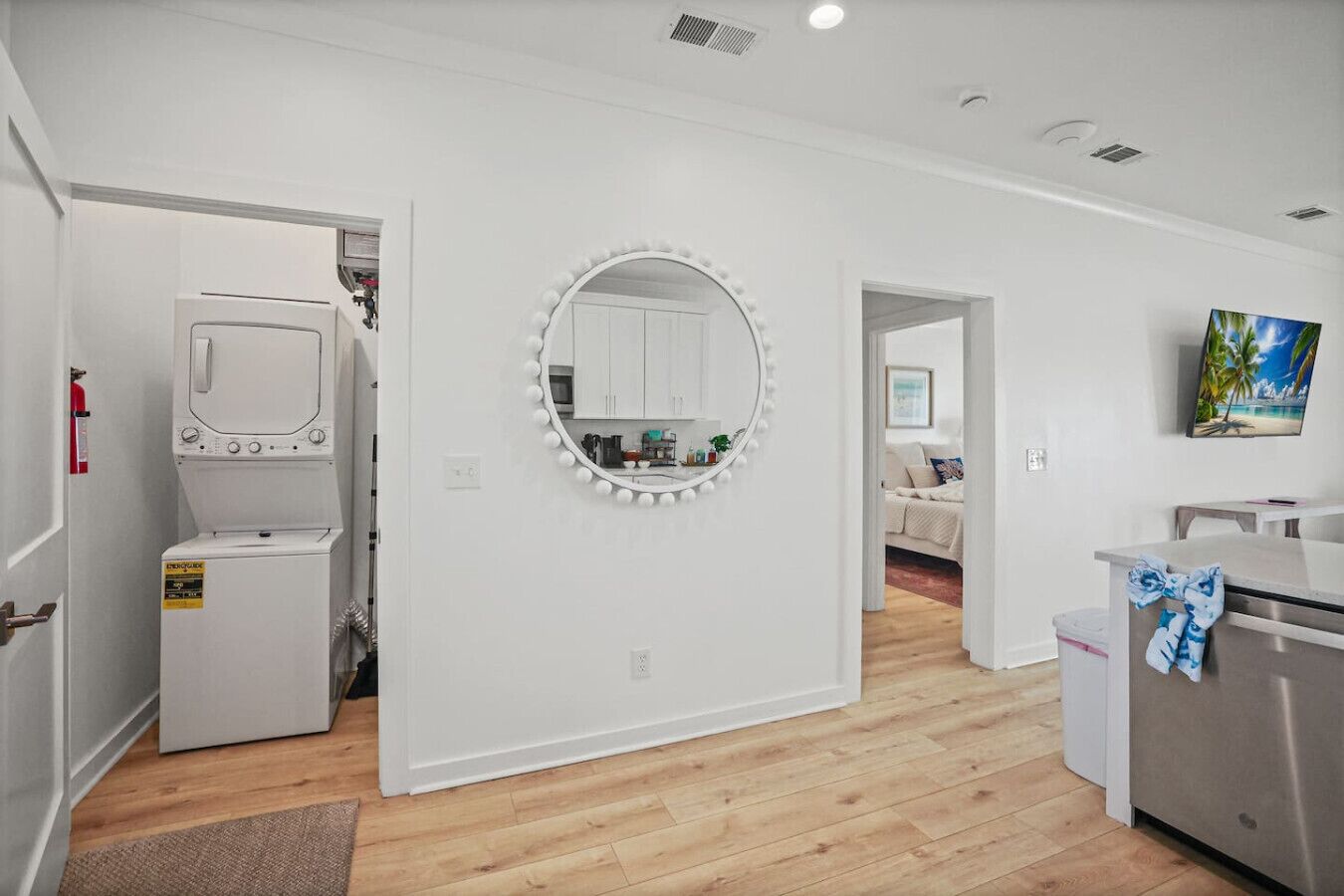 A modern kitchen with white cabinets, a built-in oven, and a large mirror with lights.