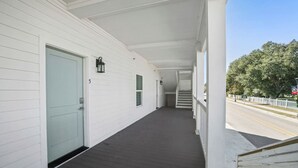 Un portico coperto con una porta blu chiaro, una piccola finestra e una scala che conduce a un secondo piano.