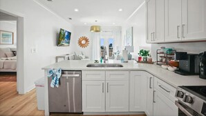 Una cucina moderna con mobili bianchi, elettrodomestici in acciaio inossidabile e un'isola centrale con lavello.